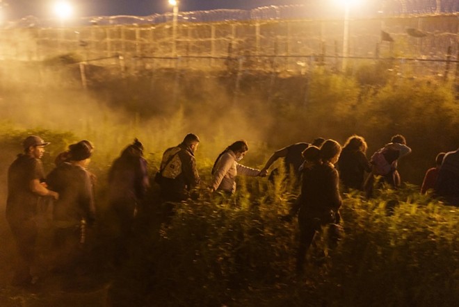 Migrants wait to cross concertina wire guarded by Texas National Guard soldiers along the U.S.-Mexico border in Ciudad Juarez, Mexico on May 27, 2024. Some experts are concerned that the National Guard is preventing people from legally seeking asylum. - Texas Tribune / Paul Ratje