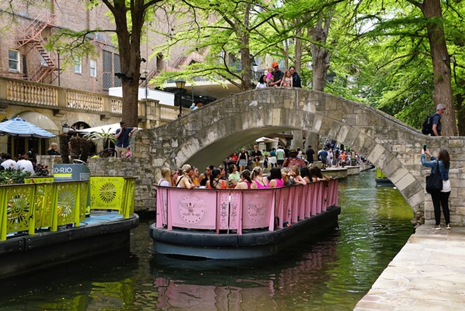 Tourists take a barge along the San Antonio River. - Shutterstock / Khairil Azhar Junos