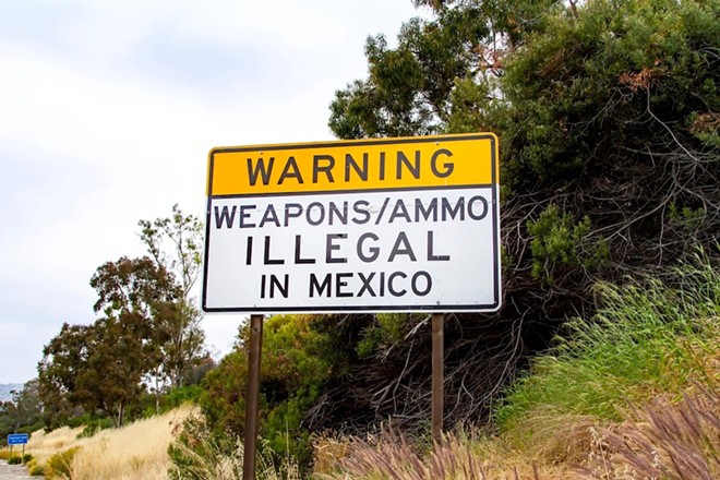 A sign near the U.S. border in San Diego warns that it's illegal to bring in guns from the United States. - Shutterstock