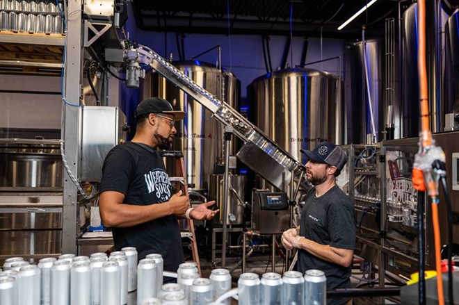 Marcus Baskerville, one of the founders of Weathered Souls Brewing Co., speaks to an employee on its production line in this 2021 photo. - Jaime Monzon