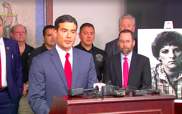 Distract Attorney Nico LaHood addresses reporters on Friday, with a dated photo of Genene Jones behind him. - SCREENSHOT, NEWS 4 VIA FACEBOOK