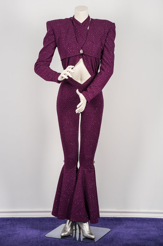 "This iconic jumpsuit was personally designed by Selena in her favorite color, purple. It was worn during her last major concert in the Houston Astrodome on February 26, 1995. The purple jumpsuit features bell bottoms and rhinestone broches at the side of both knees and at the front of the removable jacket."