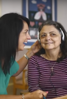 A woman suffering from dementia brightens up while listening to music with her daughter.