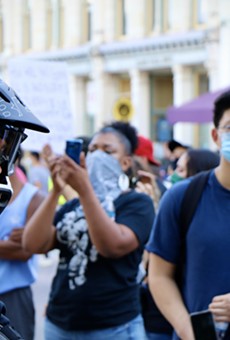 Protesters march by a San Antonio police officer at a demonstration last spring.