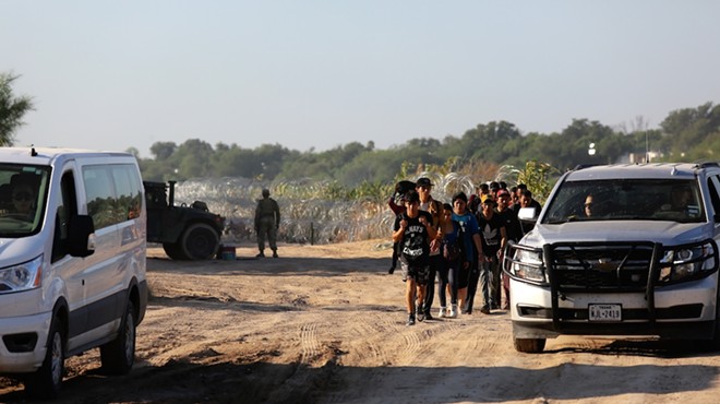 A group of migrants seeking U.S. asylum walk down a road beside the Rio Grande River to turn themselves in to the Border Patrol.